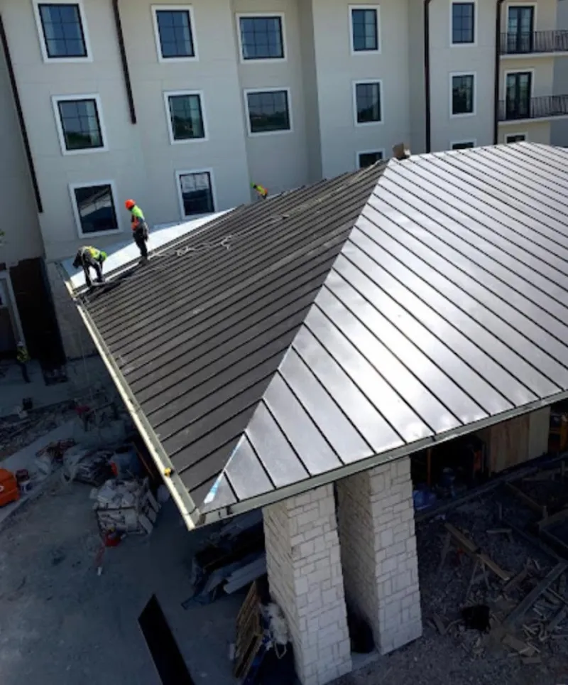 Crew installing standing seam metal roof panels on a commercial project in Providence